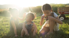 Jeff Jacobs Photography of three children playing on the grass under the sunshine.