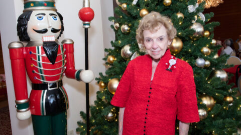Joan Wargo stands in front of the Christmas tree and Nutcracker ornament.