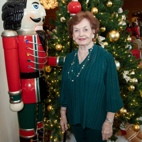 Margaret Mary Shuff poses in front of a Christmas tree and a Nutcracker ornament.