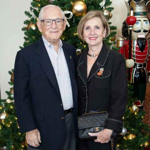 Ron and Kathy Assaf pose in front of a Christmas tree.