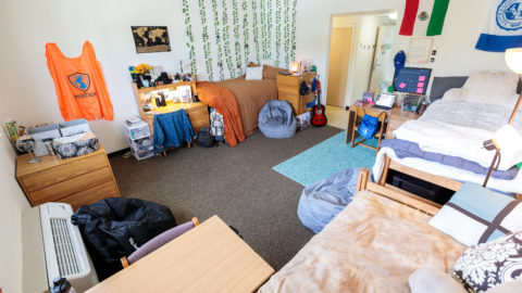 E.M. Lynn Residence Hall triple room with three twin beds, desks, and dressers. Student's decorations are featured on the walls.