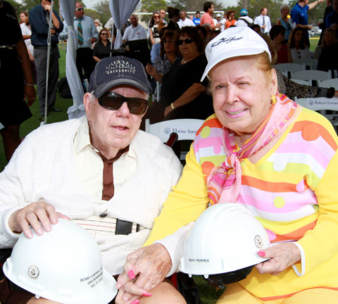 Harold and Mary Perper hold construction hats at a groundbreaking ceremony