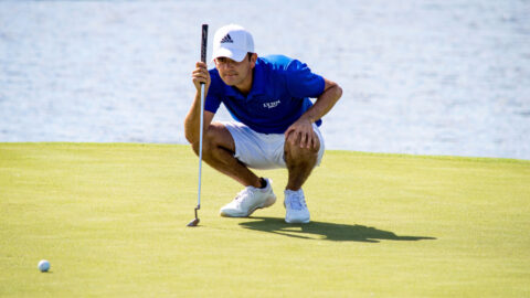 Men's golfer Toto Gana crouches down for a closer look at his next put.
