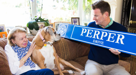 Kevin M. Ross presents Mrs. Mary Ann Perper and her dog with a new campus street sign, "Perper Drive."