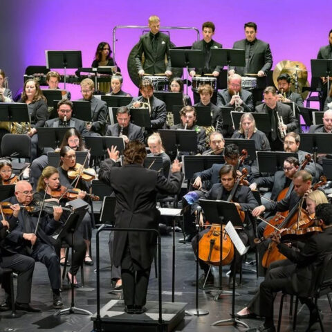 Conservatory student, devin salazar with a large orchestra performing on stage.