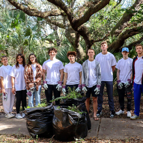 Student volunteers at Delray Oaks cleanup with a large Oak tree in the background.
