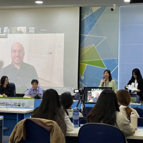 Jon Sperry remotely delivers a keynote speech on a projector in a classroom for the Taiwanese Society of Adlerian Psychology.
