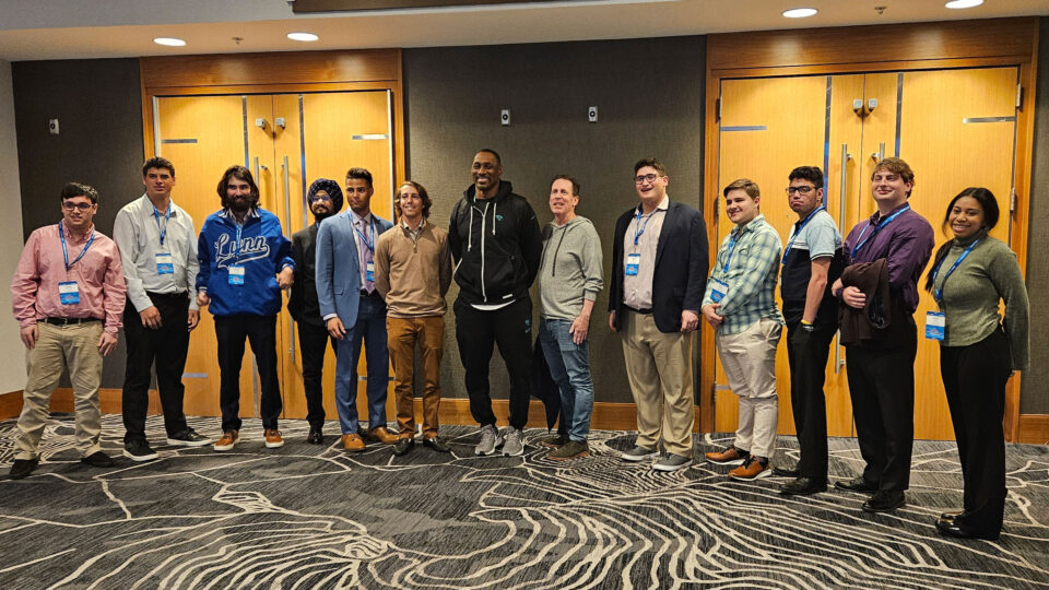 Eleven students from the College of Business and Management take a group picture inside halls of the NFL Combine event.