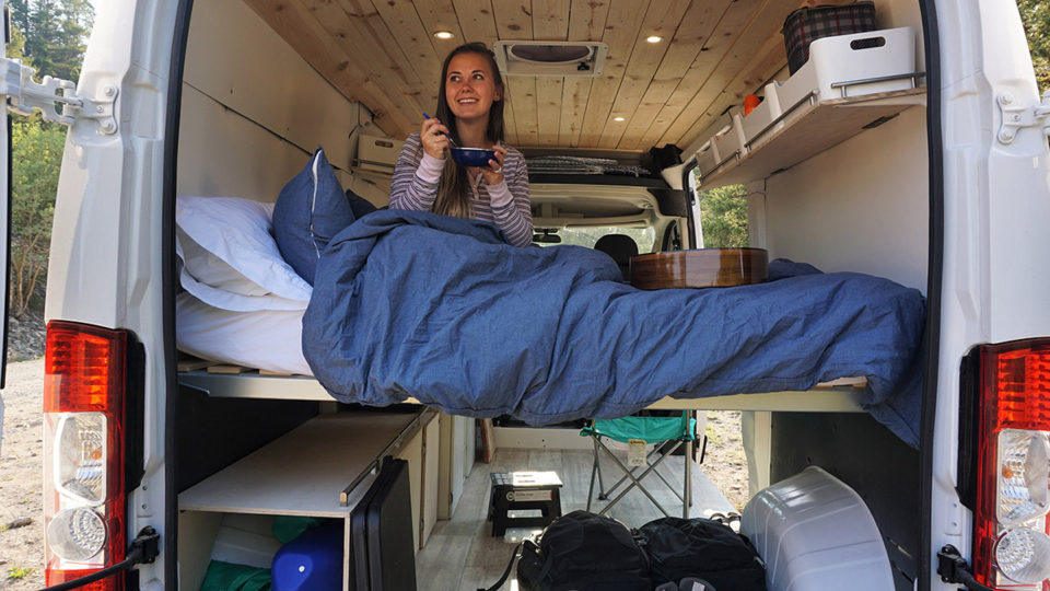 Kayla Manzano sits inside a campervan eating breakfast in bed.