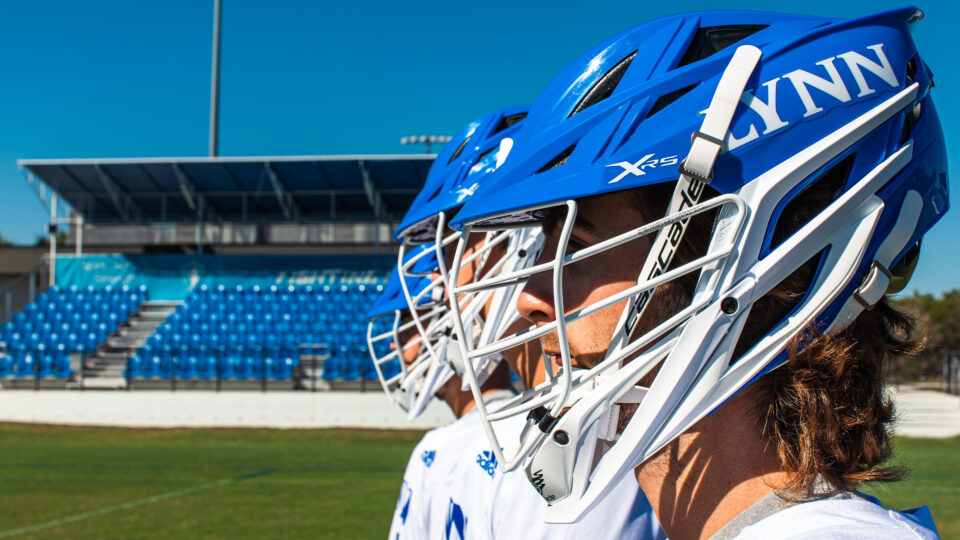 Student-athletes wearing blue lacrosse helmets.