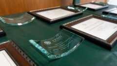 Diplomas and glass awards rest on top of a table for BSO graduation cohort II.