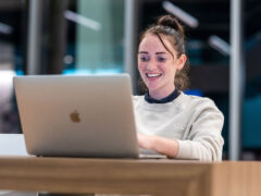 A girl smiling while using a laptop