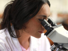 Student at Lynn University looks through microscope in the Lab.