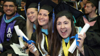 Four students smile at the camera during Commencement.