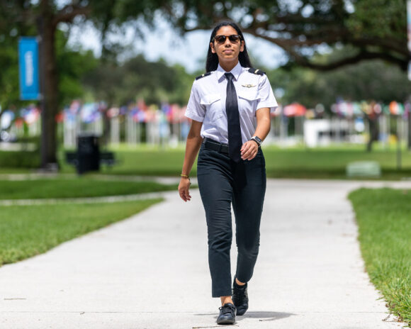 A woman aviation students walks on campus.