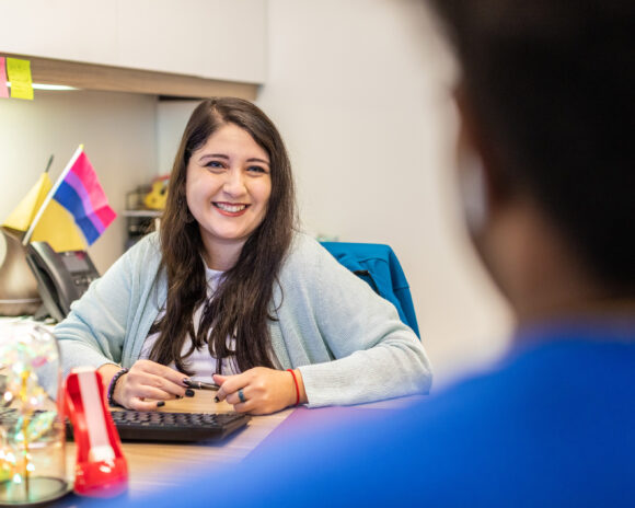 Students smile and sit opposite each other at a desk.