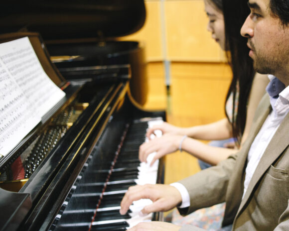 Two students play the piano in the instrumental collaborative piano program.