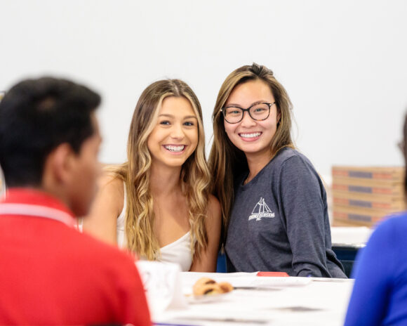Two students pose for the camera in a class.