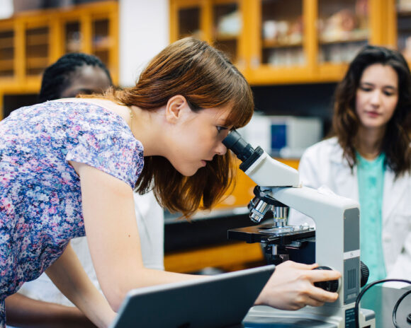 Female student looking through a microscope