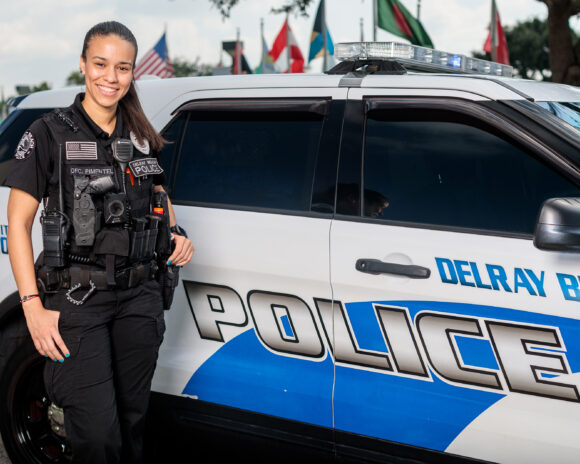 Police Officer Louise stands in front of her police car.