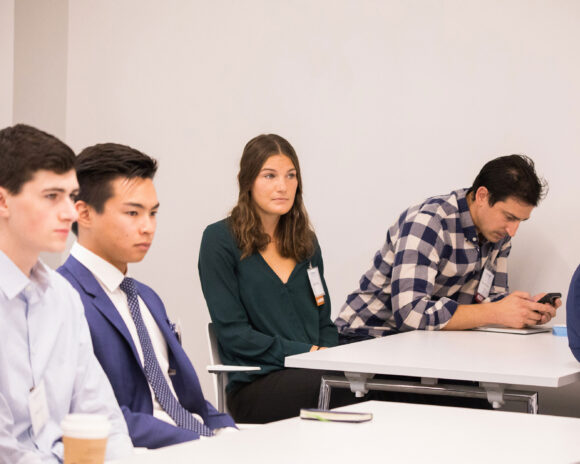 Students sit at desks during a presentation.