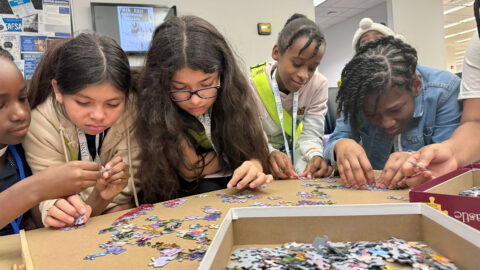 Students visiting Lynn work together on a puzzle.