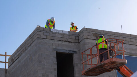 Capstone construction workers place bricks