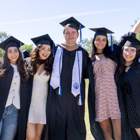 Seniors pose in their caps and gowns on Lynn's campus.