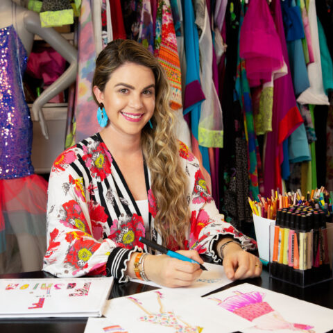 Amanda smiles in her fashion studio as she sketches a colorful dress.