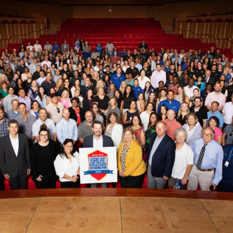Faculty and staff take a large group picture in the Keith C. and Elaine Johnson Wold Performing Arts Center