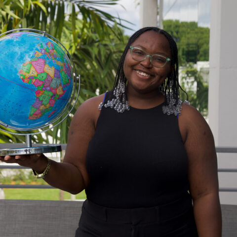 Roshana Bennett stands outside Christine's holding a globe.