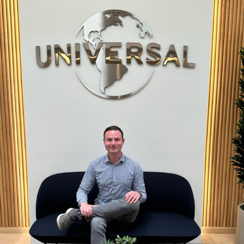 Chase Cohen sits in an office building under the official Universal Studios logo.