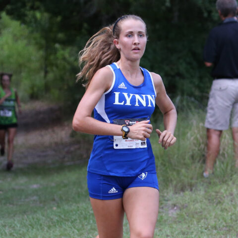 Female student athlete runs in womens cross country outdoor meet