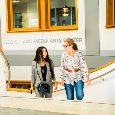 Student and professor walking up stairs to the Design and Media Arts Center in the library.