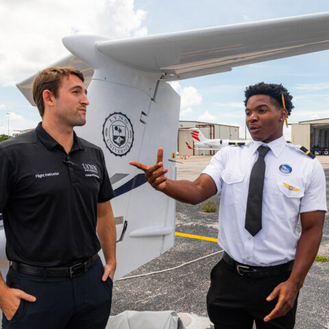 A flight instructor chats with students outside the College of Aeronautics.
