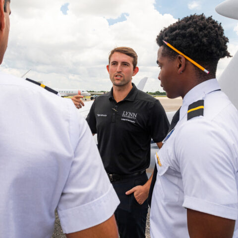 A flight instructor talks to students outside the College of Aeronautics.