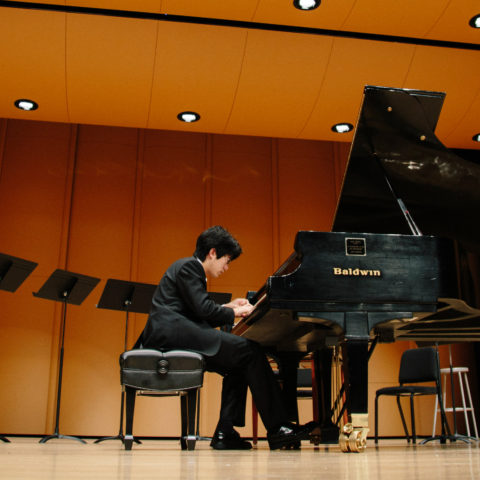 A student plays the piano on stage.