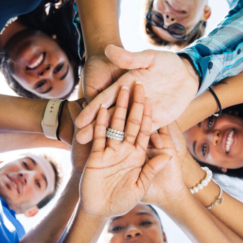 Students put their hands together in a circle.