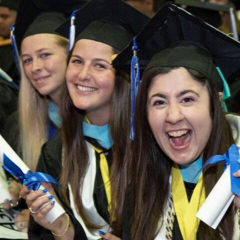 Four students smile at the camera during Commencement.