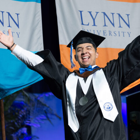 A student walks across the stage and celebrates at the 2024 Commencement Ceremony.
