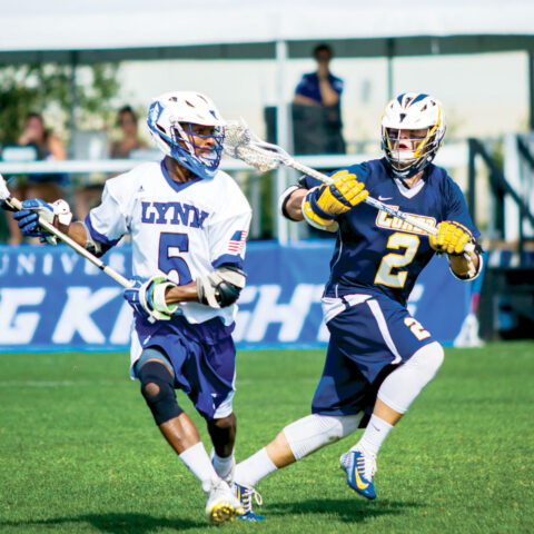 Two opposing lacrosse players compete on the field