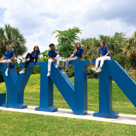 Six Lynn students sit on top of the life-size Lynn letters in Christine's Park.