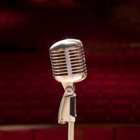 A single vintage microphone stands onstage in the Wold Performing Arts Center.
