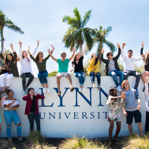 Students sit and cheer on the Lynn University sign.