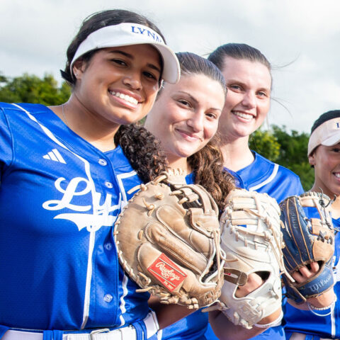 Lynn University's softball team takes a group picture with their uniforms and gloves.