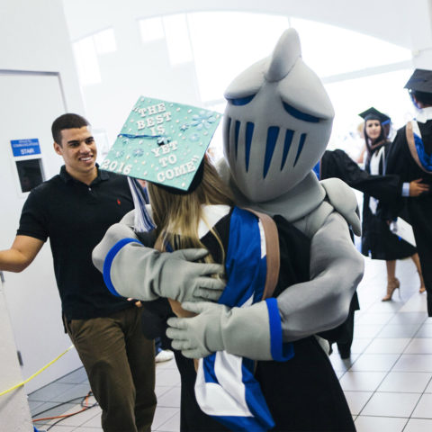 Lynn mascot Lance hugs graduating student.