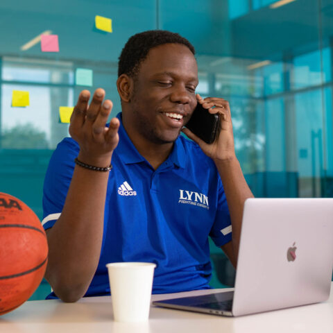 Sports management student smiling and talking on phone at Snyder Idea Lab.