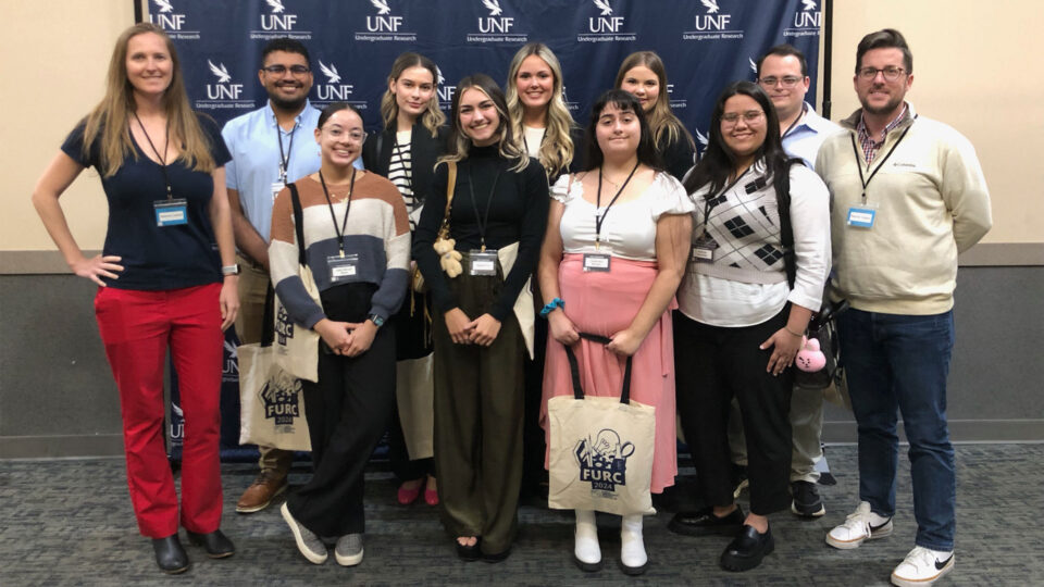Alanna Lecher stands with nine Lynn students at the Florida Undergraduate Research conference.