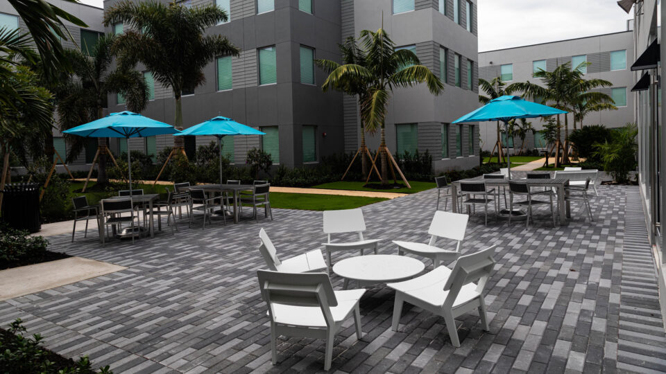 The private interior courtyard section of Capstone Apartments, filled with chairs, tables and palm trees.