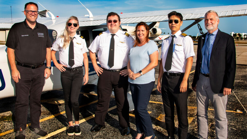 Dempsey (second left) smiles with members of the aeronautics program outside of an airport.
